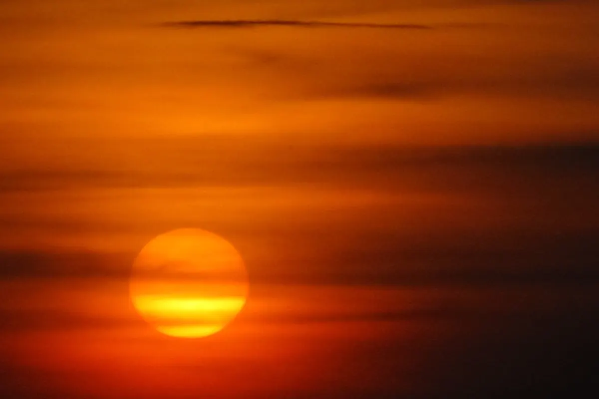 Sun rising through an orange sky over Amboseli National Park